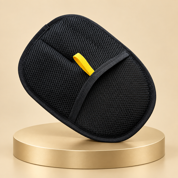 Pet hair remover mitt in black with a mesh back and yellow loop, tilted on a round champagne plinth