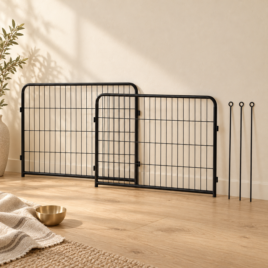 Two overlapping black dog playpen extension panels leaning against a cream wall with three rods beside them.