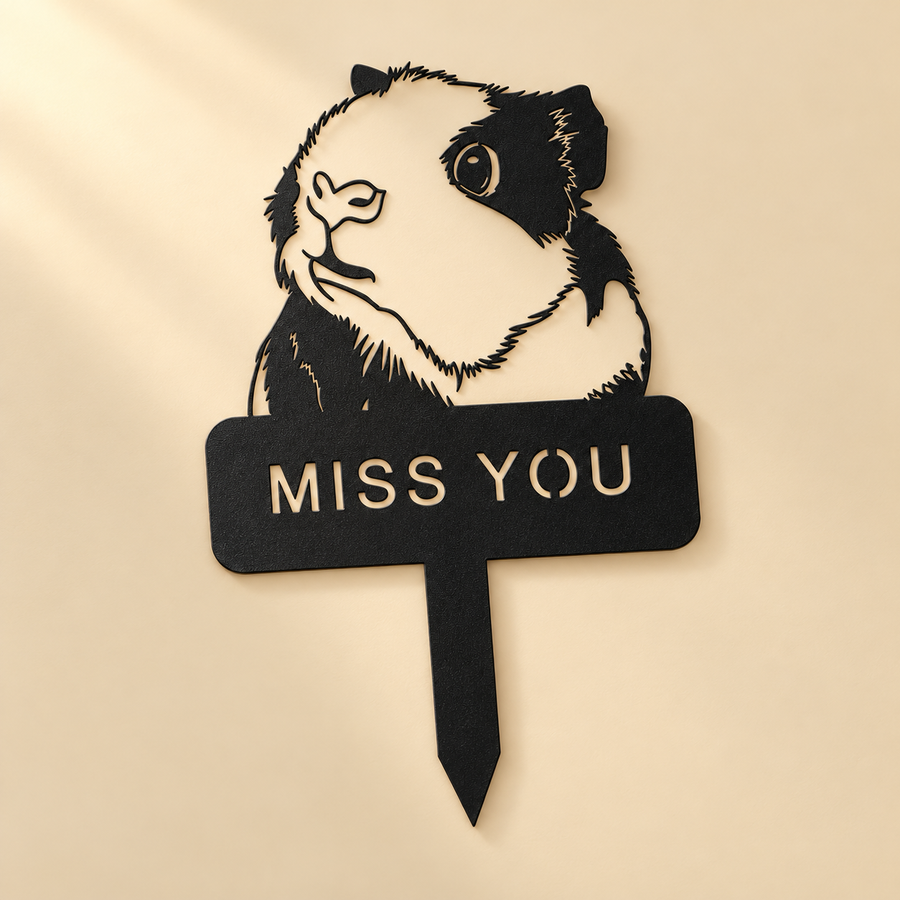 One black metal guinea pig memorial stake with a pointed stem laid flat on a champagne surface