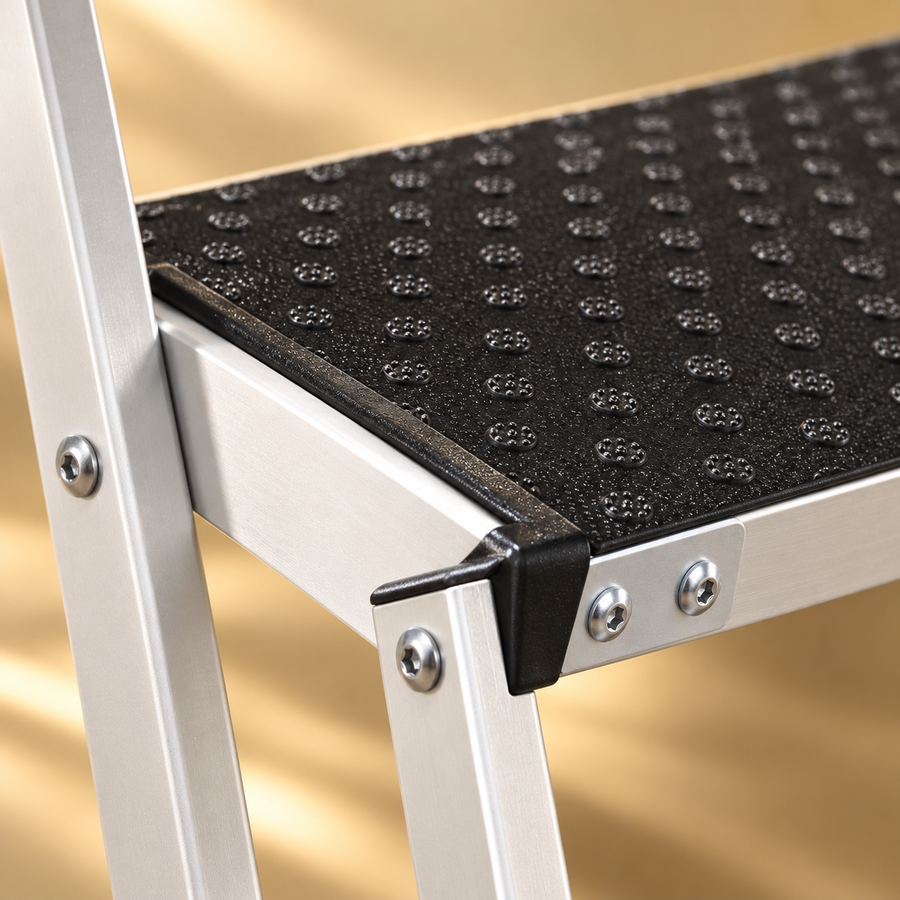 Close view of a dotted black stair tread, silver rectangular frame and the fasteners at the corner.