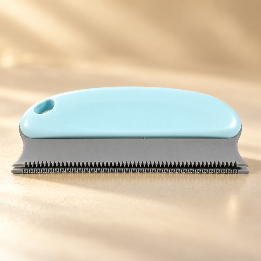 Pale blue contoured grip, hanging hole and gray flexible toothed edge of a handheld pet hair remover
