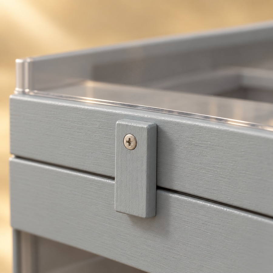 Close-up of a gray wooden turn latch and painted wood grain beside a clear front panel on a hamster cage