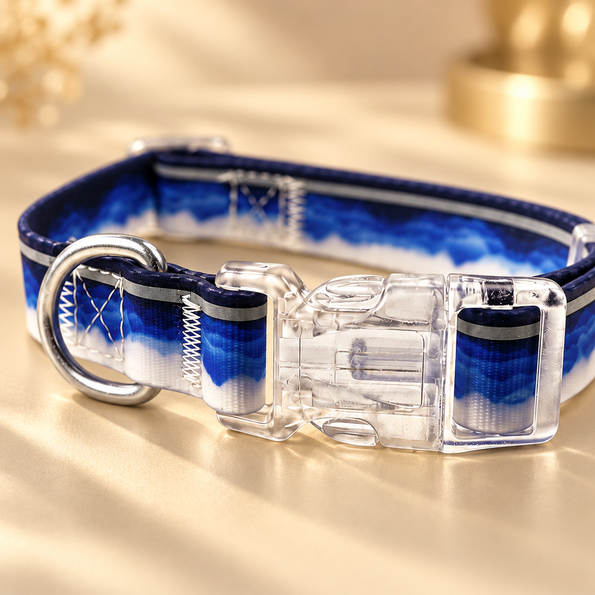 Clear buckle and silver ring beside white cloud patches on a navy dog collar in warm light