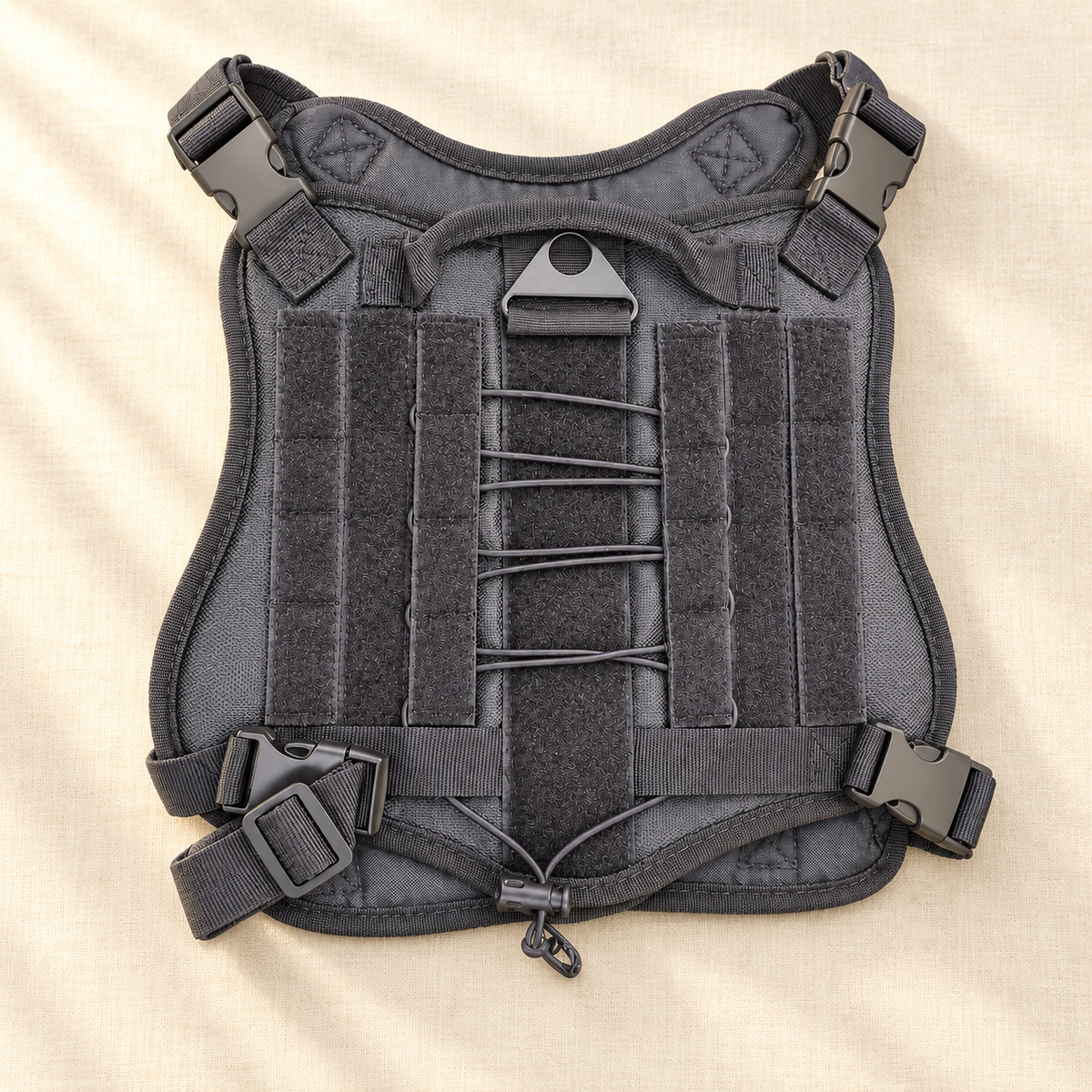 Gray dog harness lying flat on a pale surface with central cord lacing and four dark strap fittings