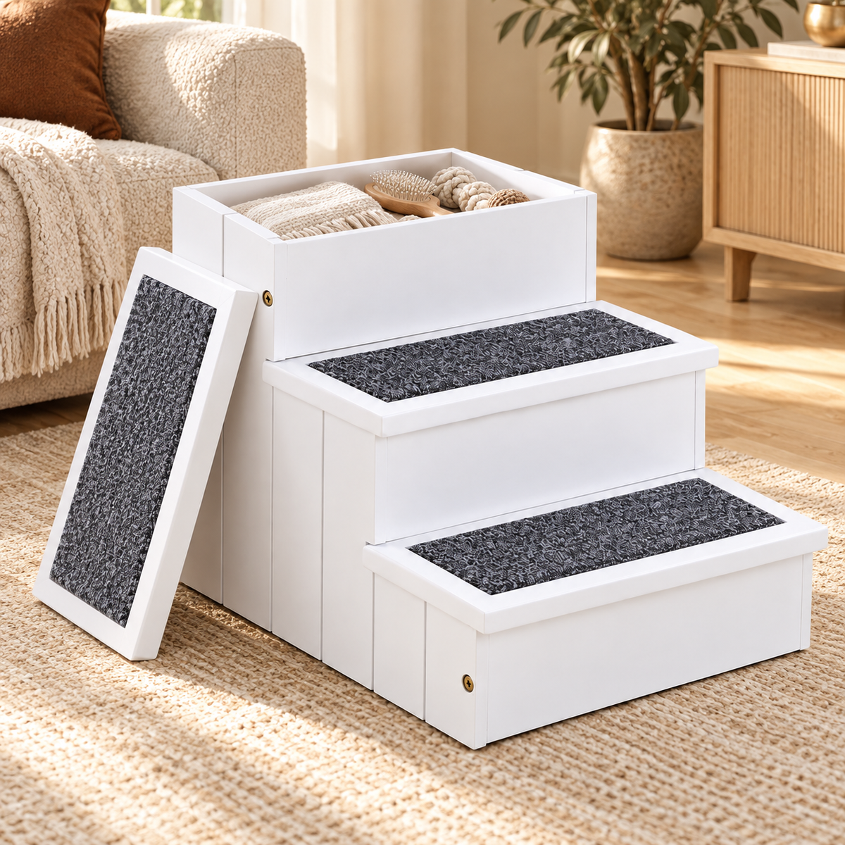 White wooden three-step pet stairs with a storage box on top holding blankets and a gray carpeted lid leaning at the side