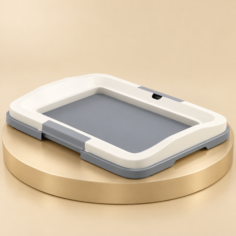 Gray dog training-pad tray with a white retaining frame and low front opening on a round beige platform.