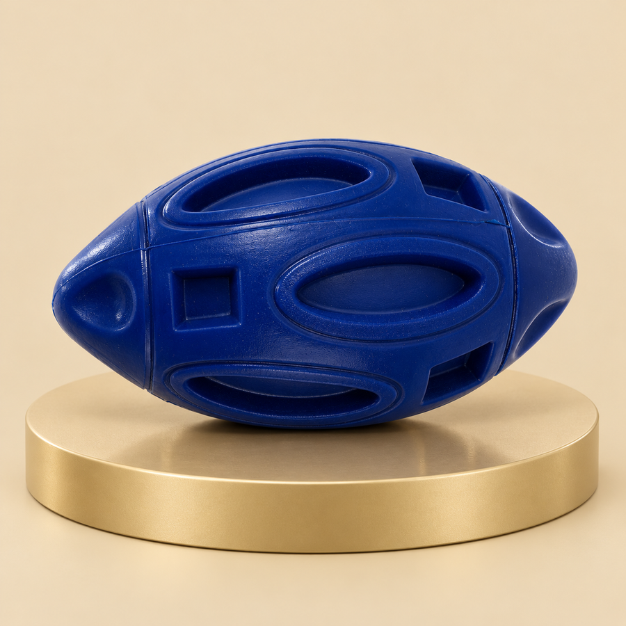Navy rubber football dog toy with raised oval panels and square recesses on a round champagne plinth