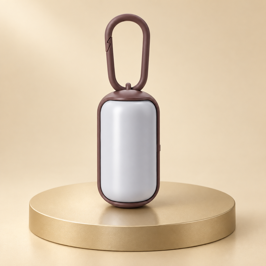 White waste bag dispenser with a brown carabiner and brown trim, standing on a round champagne plinth